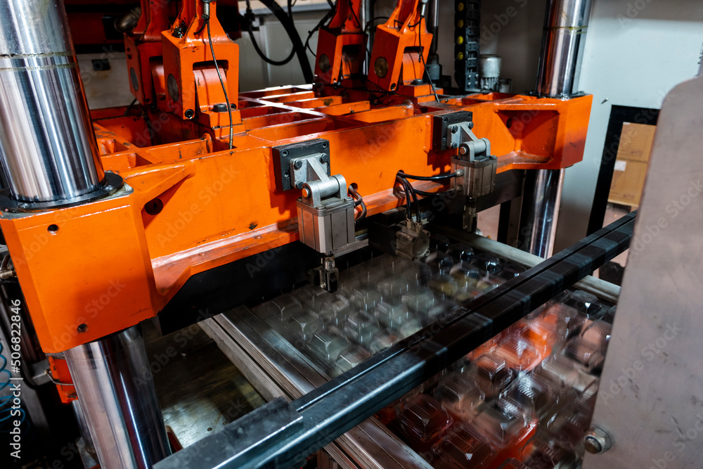 Vacuum thermoforming machine is used for producing plastic packaging in the factory. Close-up of the machine making a mold. Selective focus front Vacuum thermoforming machine is used for producing plastic packaging in the factory. Close-up of the machine making a mold. Selective focus front