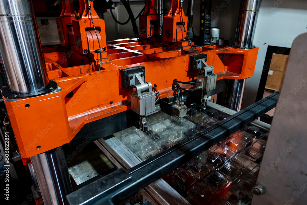 Vacuum thermoforming machine is used for producing plastic packaging in the factory. Close-up of the machine making a mold. Selective focus front Vacuum thermoforming machine is used for producing plastic packaging in the factory. Close-up of the machine making a mold. Selective focus front
