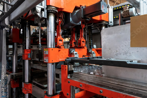 Vacuum thermoforming machine is used for producing plastic packaging in the factory. Close-up of the machine making a mold. Selective focus front