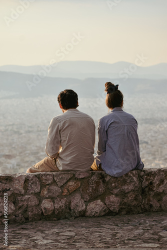 Couple enjoying the view from the top of Mount Lycabettus in Athens on a small stone bench © Alexzander Keranis