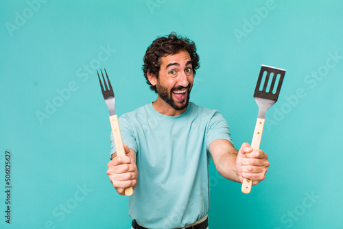 Fototapete young adult hispanic crazy man with barbecue tools