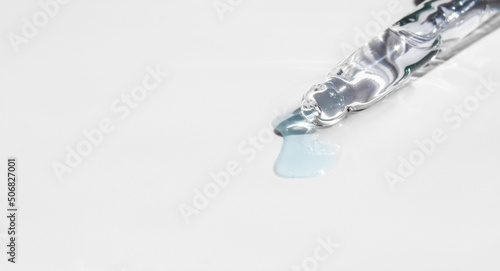 Pipette with fluid hyaluronic acid on blue background. Cosmetics and healthcare concept closeup. Dose of serum, retinol with air bubbles. Flat lay. Luxury beauty product presentation, macro. Banner