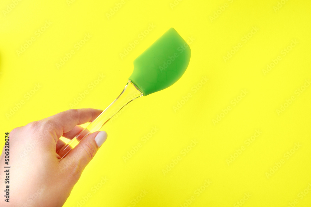 Womans hand holding silicone green spatula with plastic handle on color background- Image Womans hand holding silicone green spatula with plastic handle on color background- Image