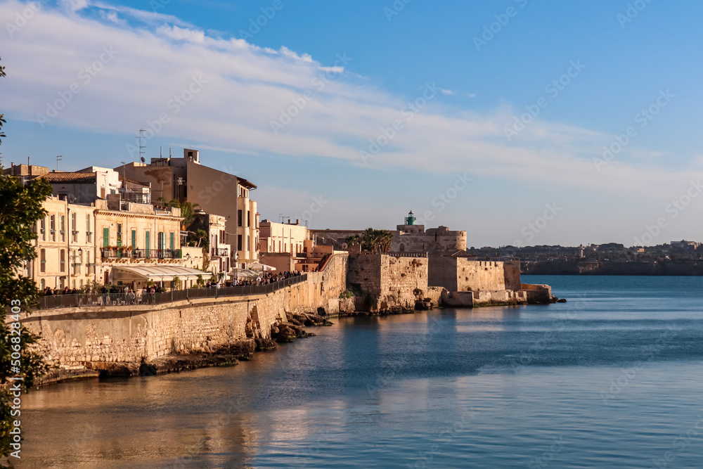 Panoramic view on the waterfront of the city of  Syracuse, Sicily, Italy, Europe EU. Soft light shining on the residential houses at the Mediterranean seaside. Walking along the coastline