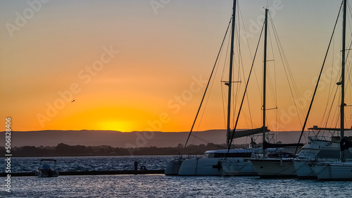 Panoramic view during sunset on the harbor of Ortigia island in the city Syracuse, Sicily, Italy, Europe, EU. Boat and yachts flowing in the Siracusa bay in the Mediterranean Sea. Vacation seaside