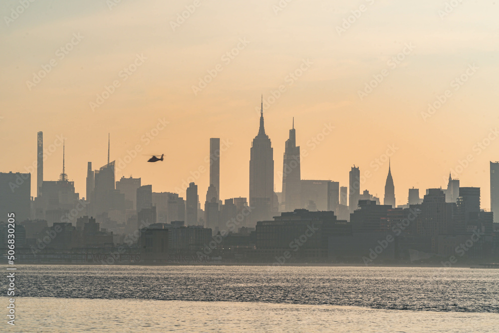 Vivid Manhattan skyline morning sunrise with helicopter flaying across the buildings, travel tourism theme USA city, world famous destination. Horizontal photograph.