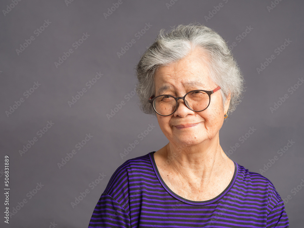 Portrait of a senior woman looking at the camera with a smile while standing over a gray background Portrait of a senior woman looking at the camera with a smile while standing over a gray background