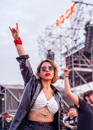 Young woman makes horns gesture at rock music festival photo