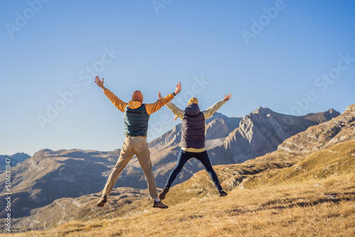 Montenegro. Happy couple woman and man tourists in the background of Durmitor National Park. Saddle Pass. Alpine meadows. Mountain landscape. Travel around Montenegro concept