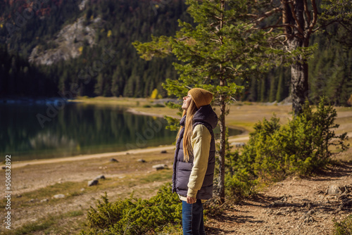 Woman tourist in background of Panoramic morning view of Black Lake Crno Jezero. Calm summer scene of Durmitor Nacionalni Park, Zabljak location, Montenegro, Europe. Beauty of nature concept photo