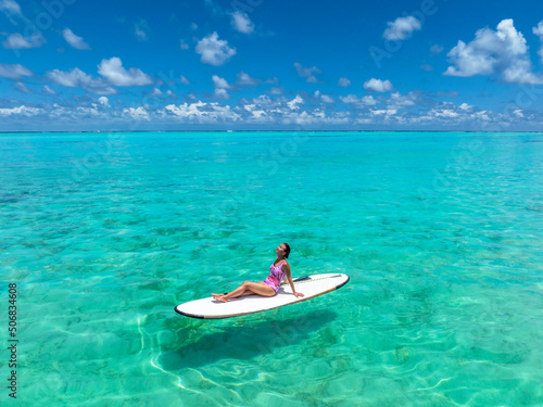 Beautiful woman on a surf board is sunbathing in a bikini. Maldives beaches  tourist paradise. 
Travel Maldives islands