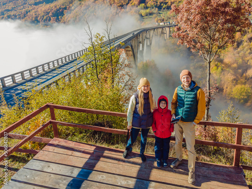 Montenegro. Happy family on the background of Dzhurdzhevich Bridge Over The River Tara foggy morning photo
