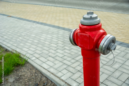 Fototapeta Naklejka Na Ścianę i Meble -  Red fire hydrant standing by the town footpath