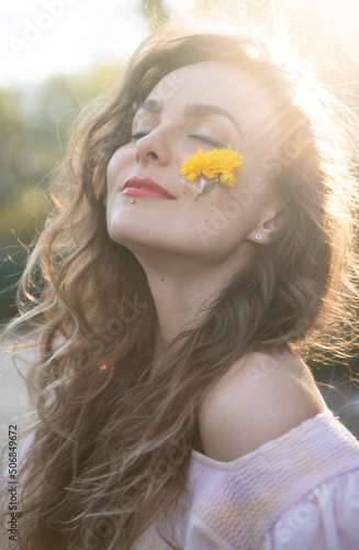 curly hair woman with blue eyes and yellow flower on face