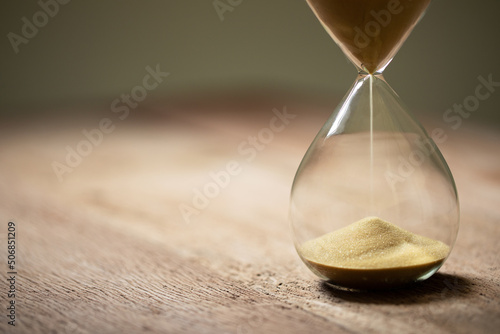 hourglass (sand clock) on an old wooden table, deadline for doing business, elapsed time concept, copy space