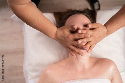 Close-up young woman enjoying massage in spa salon  facial beauty treatment. woman getting spa massage treatment at beauty salon. top view