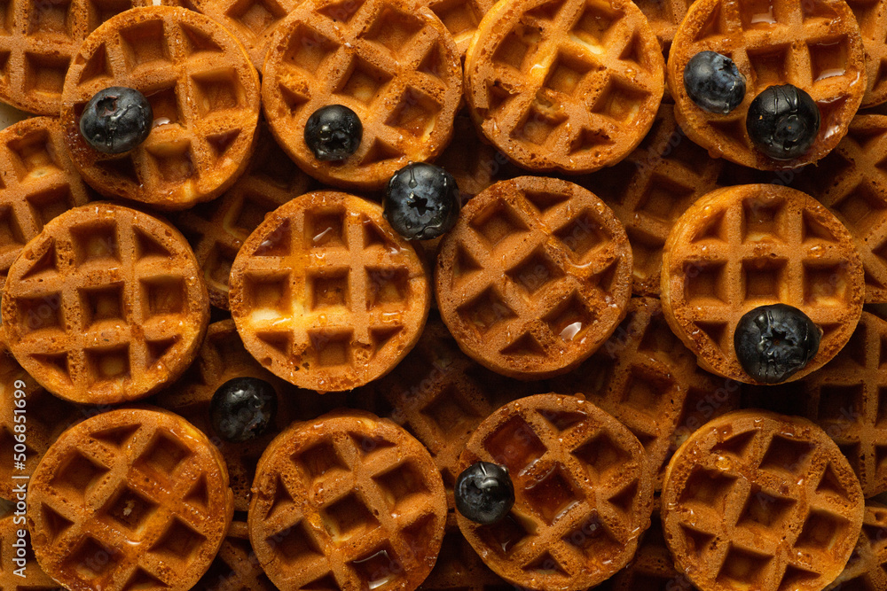 Fototapeta premium Soft round fried waffles on a beige background. Monochrome pattern with hard shadows.