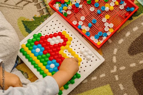 Toddler playing pegboard mosaic. Early child development. Fine motor skills. Learn and creativity