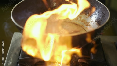 Close up of cooking food with flame in a frying pan. Slow motion.4K. Chef is tossing chicken meat on a pan.Cooking flambe style chicken .