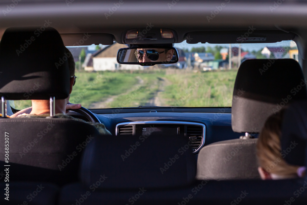 Reflection of elegant business man in car rear view mirror, man drives in sunglasses looking road. Reflection of elegant business man in car rear view mirror, man drives in sunglasses looking road.