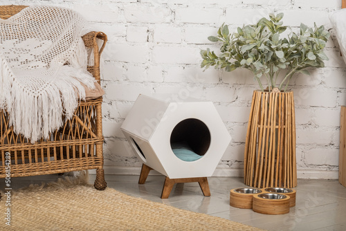 A cozy corner for a pet: a pet house, bowls for food and drink.