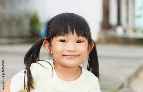 Portrait​ image of​ 4-5​ years old​ baby​ toddler. Face of smiling​ Asian​ girl in head shot. Happy​ kid playing​ at the park playground.