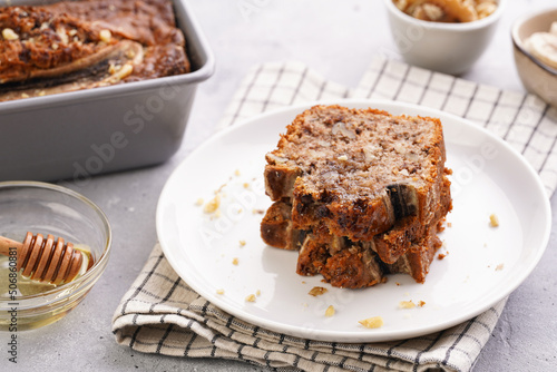 Slices of Chocolate banana bread with walnuts on a checkered kitchen napkin and ingredients on a grey neutral background