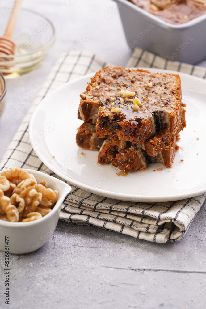 Slices of Chocolate banana bread with walnuts on a checkered kitchen napkin and ingredients on a grey neutral background Slices of Chocolate banana bread with walnuts on a checkered kitchen napkin and ingredients on a grey neutral background