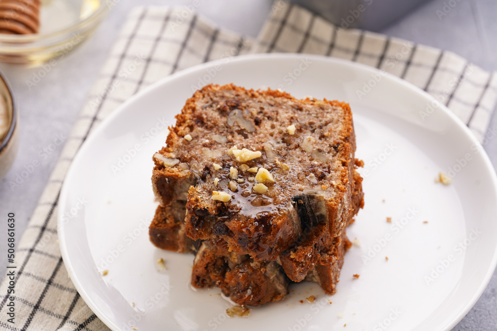 Slices of Chocolate banana bread with walnuts on a checkered kitchen napkin and ingredients on a grey neutral background