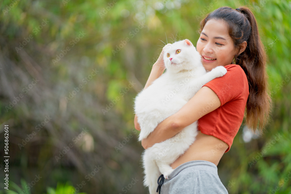 Asian pretty woman hold and hug white cat with happiness in garden with day light. Asian pretty woman hold and hug white cat with happiness in garden with day light.