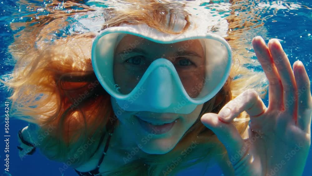 Young woman swims underwater and shows OK signal with her hand Young woman swims underwater and shows OK signal with her hand