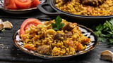 Eastern Uzbek cuisine. Pilaf from Bulgur groats with veal and lamb with carrots. Bulgur pilaf lies in an Uzbek plate with a national pattern on a woody black background.