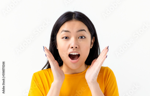 Fotografija Portrait of thrilled Asian woman with open mouth holding hands near face isolate