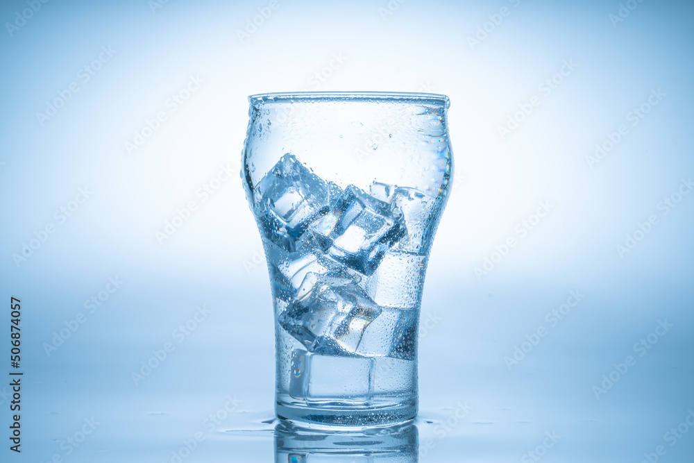 Ice cube fell into the glass of water.Water splashed from the clear glass.Fresh concept