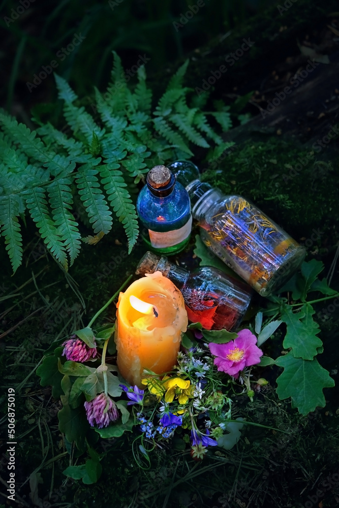 Burning candle, magic witch bottles, flowers on dark forest natural background. Magic ritual, Witchcraft, spiritual practice. pagan, Wiccan, Slavic traditions. esoteric ritual for Midsummer, Litha - obrazy, fototapety, plakaty 