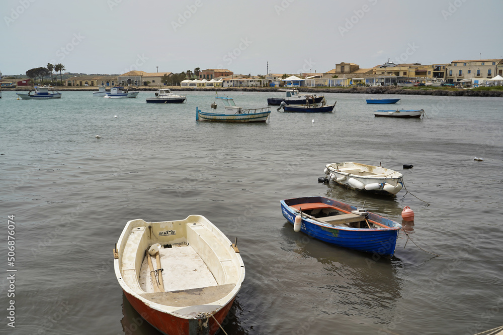 Sicily, Italy - April 16, 2022: Sea coast with moored boats and fishing boats. Fishing village.