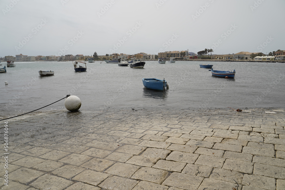 Sicily, Italy - April 16, 2022: Sea coast with moored boats and fishing boats. Fishing village.