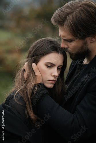 A young couple in love in black coats walks in the countryside in the rain. Autumn gloomy mood. cinematic image