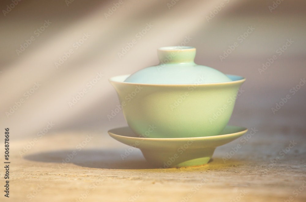 Gaiwan on the marble floor is a selective focus in the rays of the sun. Gongfu cha tea ceremony. Chinese ceramics of Zhu Yao. Chinese porcelain. Gaiwan tea cup and lid. Tea bowl with lid. Puer. Gaiwan on the marble floor is a selective focus in the rays of the sun. Gongfu cha tea ceremony. Chinese ceramics of Zhu Yao. Chinese porcelain. Gaiwan tea cup and lid. Tea bowl with lid. Puer.
