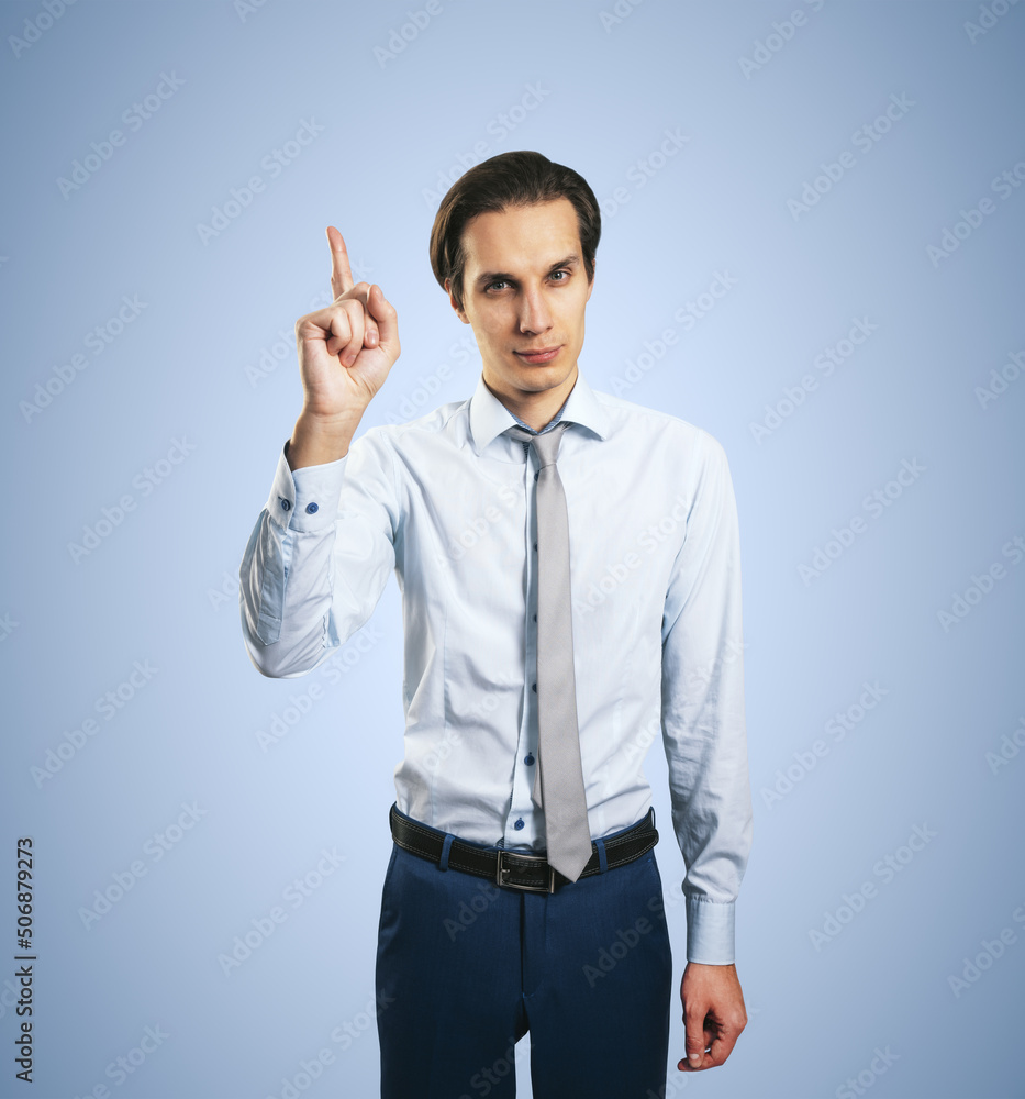 Warning concept wih young handsome man in white shirt with raising hand and forefinger isolated on light blue wall background, closeup Warning concept wih young handsome man in white shirt with raising hand and forefinger isolated on light blue wall background, closeup