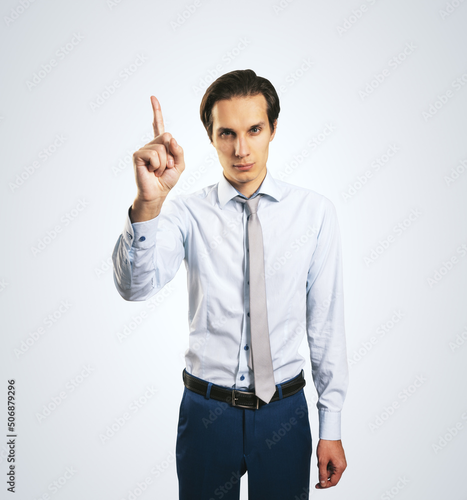 Warning and notification concept with young man with rising up index finger isolated on light grey wall background, closeup Warning and notification concept with young man with rising up index finger isolated on light grey wall background, closeup