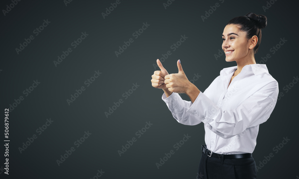 Like concept with happy young businesswoman in white shirt holding thumbs up on abstract black wall background with blank space for you logo, mock up Like concept with happy young businesswoman in white shirt holding thumbs up on abstract black wall background with blank space for you logo, mock up