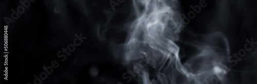 Smoke rises in the air on a black background.
