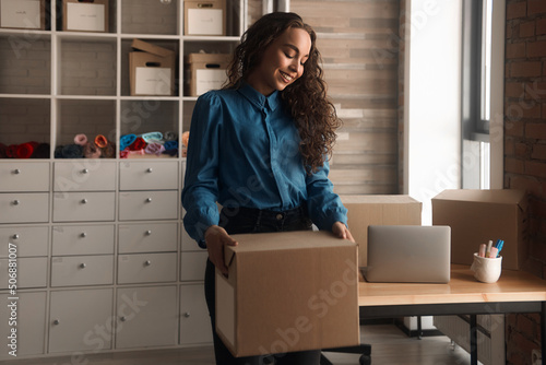 Young Asian curly-haired logistics worker packs goods, collects parcels, puts things in a carton box, prepares a parcel for shipment, transports, collects donations, business owner, delivery © Alexandr