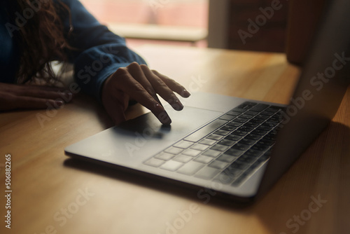 Side view. Young business woman is sitting at the table and. On the table is a laptop, smartphone and. On the computer screen graphs and charts. The student is studying online. Blogger. entrepreneur