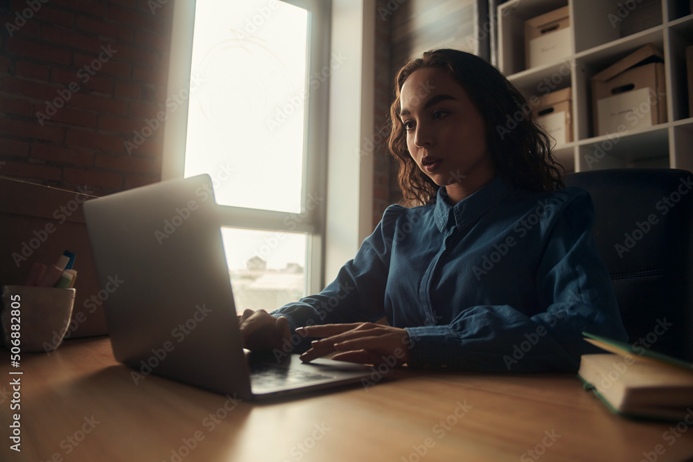 Side view. Young business woman is sitting at the table and. On the table is a laptop, smartphone and. On the computer screen graphs and charts. The student is studying online. Blogger. entrepreneur Side view. Young business woman is sitting at the table and. On the table is a laptop, smartphone and. On the computer screen graphs and charts. The student is studying online. Blogger. entrepreneur