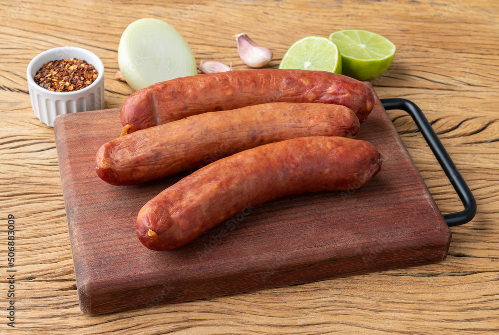Calabrese pork sausage over wooden board with seasonings Calabrese pork sausage over wooden board with seasonings