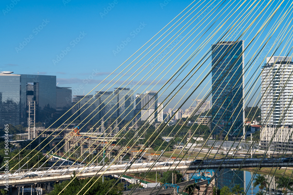 Fototapeta premium Aerial view of the Marginal Pinheiros Avenue, Octavio Frias de Oliveira Cable stayed bridge, Pinheiros River, corporate buildings and skyline of Sao Paulo city in sunny summer day. Brazil.