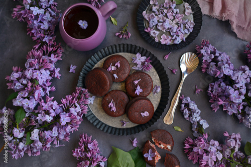 Slika na platnu Spring floral background with lilacs, chocolate chip cookies and a cup of tea