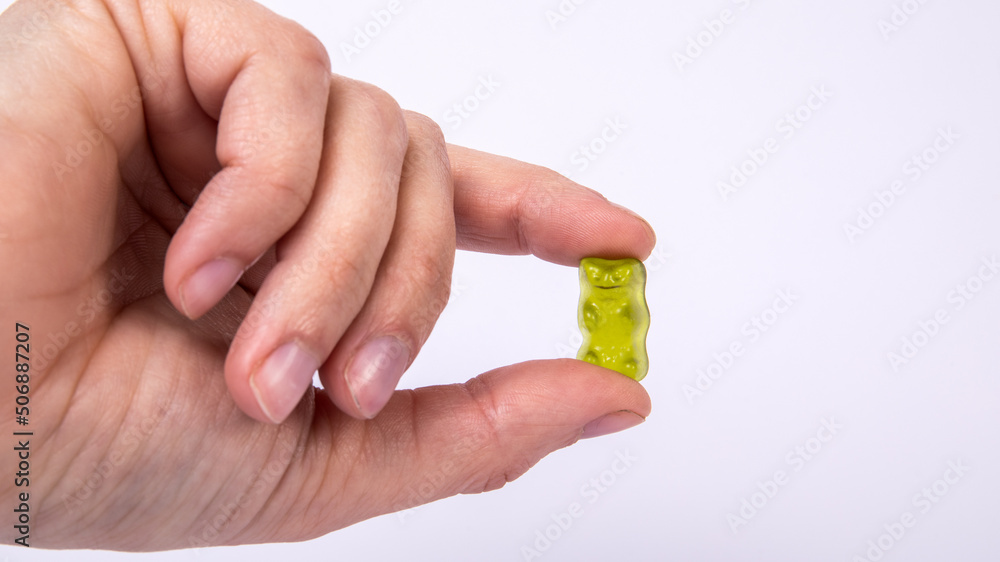 Green rubber candy bear in hand of woman on a white background Green rubber candy bear in hand of woman on a white background